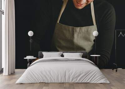 Young man kneading dough on dark background. Wall mural