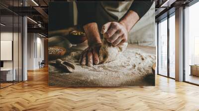 Young man kneading dough on dark background. Wall mural