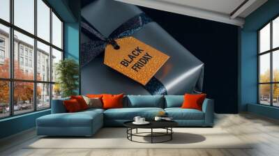 Black Friday gift wrapped in metallic paper with a sparkling tag, illuminated by soft glitters Wall mural