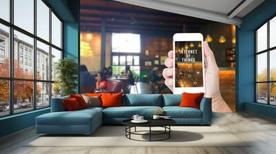 hand holding mobile phone with internet of things word with blur Wall mural