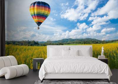 hot air balloon over yellow flower fields against blue sky Wall mural