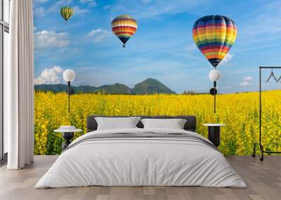 Hot air balloon over yellow flower fields against blue sky Wall mural