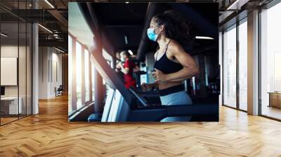 Active fitness woman wearing hygienic protective face mask while training in gym to protect herself and others against coronavirus or covid-19. Stay safe and healthy. Wall mural