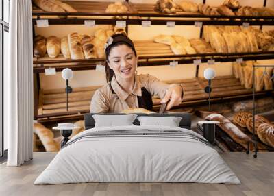 Beautiful smiling bakery worker selling fresh pastry to the customer in bakery shop. Wall mural