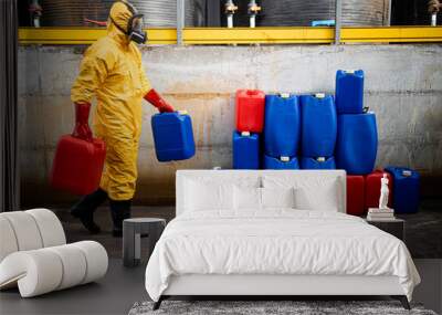 Chemical worker in hazmat protection suit and gas mask carrying canisters with hazardous material inside production factory. Wall mural