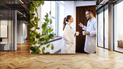 Doctors having relaxed conversation during coffee break. Wall mural