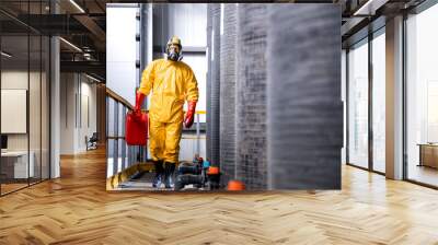 Experienced factory worker in protective equipment and gas mask carrying aggressive chemicals. Wall mural