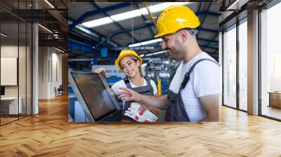 Factory worker explaining trainee how to operate industrial machine using new software on touch screen computer. People working at production line. Wall mural