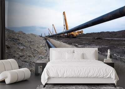 Gas pipeline construction. Heavy duty construction machines placing gas pipe into the ground. Wall mural