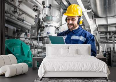 Industrial engineer standing by gas generator in power plant and controlling electricity production on his tablet. Wall mural