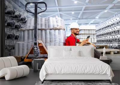 Lazy factory worker sitting and using mobile phone at job. Wall mural