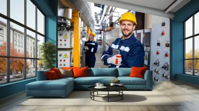 Portrait of an industrial electric engineer standing by power supply inside oil refinery. Wall mural