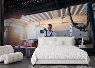 Portrait of smiling mechanic standing in truck repair shop. Vehicle service and truck maintenance. Wall mural