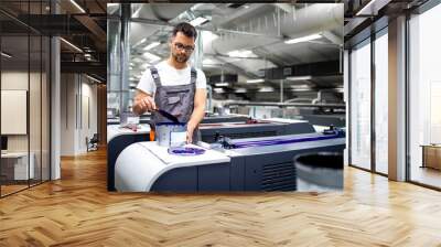 Printing machine operator preparing paint for print process in printing house. Wall mural