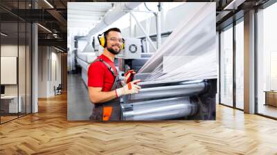 Production line worker standing by machine and controlling plastic bag manufacture. Wall mural