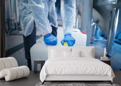 Shot of an unrecognizable industrial worker technologist with protective rubber gloves opening plastic can with chemicals in factory. Wall mural