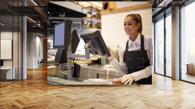 Supermarket worker measuring and selling meat to the customer. Working in grocery store. Wall mural