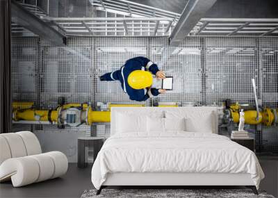 Top view of refinery worker walking by gas pipes, checking gasoline supply and installations in production plant. Wall mural