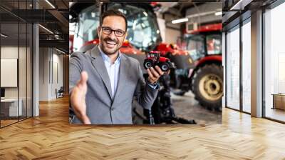 Tractor salesman standing in workshop and guarantee spare parts and service of agricultural machines. Wall mural