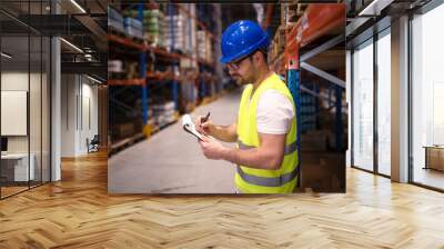 Warehouse worker checking inventory in large distribution center. Controlling goods storage and distribution. Wall mural