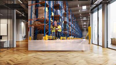 Warehouse workers discussing about logistics and distribution packages to the market. Teamwork in warehouse storage center. Wall mural