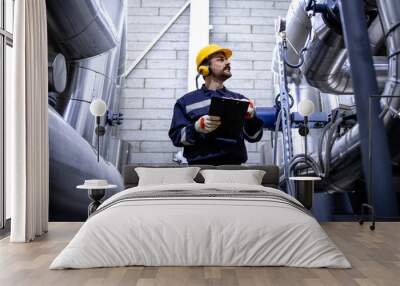 Worker checking pipes in city heating plant. Wall mural