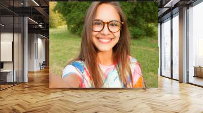 close up portrait of a young attractive woman holding a smartphone and taking a selfie Wall mural