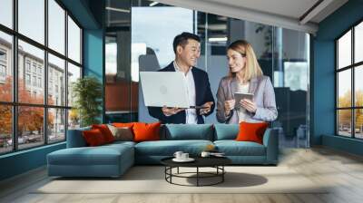 A group of business people stand in the hallway and discuss about problems in the company. Person employees using laptop and digital tablet in office. Thoughtful asian busy managers keeping gadget Wall mural