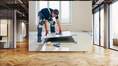 A male construction worker installs a large ceramic tile Wall mural