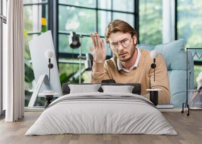 Angry businessman holding phone, shouting and waving hand, sitting at desk in office, upset about bad news, angry at non-working phone. Wall mural