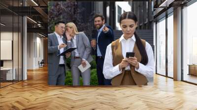 Bullying and Harassment at workplace in office, employees discussing with colleague on lunch break outside office building. Wall mural