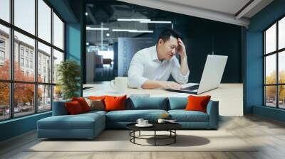 Businessman desperation, asian man working in office, looking at laptop screen, screaming in grief, got bad news Wall mural