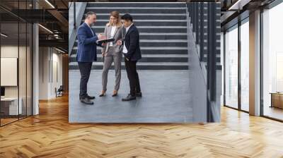 Colleagues company employees talking and discussing business plans outside office building, diverse business team men and women discussing financial reports and contract documents on stairs Wall mural