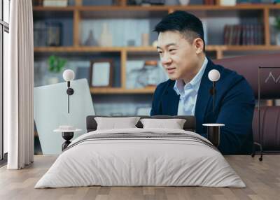 Concentrated businessman working on laptop in classic office, looking at monitor screen Wall mural