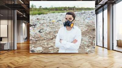 Female scientist in a protective respirator mask at a landfill assesses the level of environmental pollution Wall mural