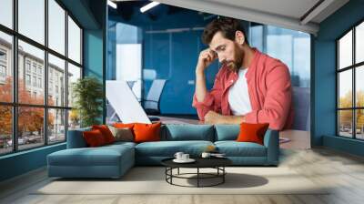 Frustrated businessman depressed at workplace working on laptop, man in shirt upset and sad displeased with bad work results and achievement inside office. Wall mural