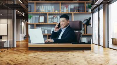 Happy asian boss banker talking on the phone working in a classic office on a laptop Wall mural