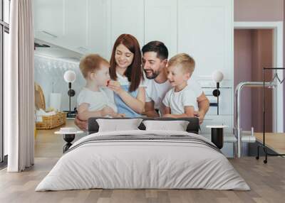 Happy family, husband woman and two children boys, having breakfast at home in the kitchen, and spending happily together Wall mural