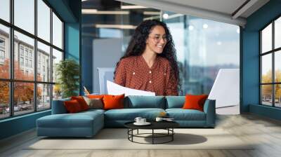 latin american businesswoman working inside office with documents and laptop, worker paperwork calculates financial indicators smiling and happy with success and results of achievement and work Wall mural