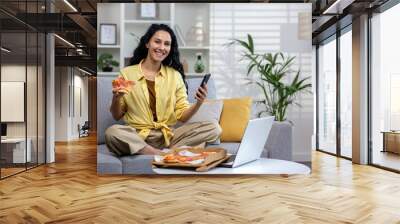 Portrait of happy online food delivery customer shopper woman, Hispanic woman smiling and looking at camera, using app on phone to order pizza delivery. Wall mural