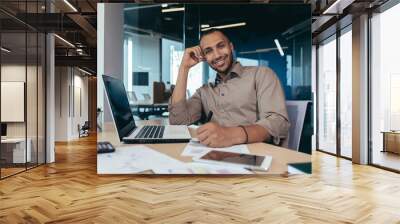 portrait of successful hispanic businessman inside office, man with laptop working typing on keyboar Wall mural