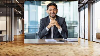 Portrait of young hispanic businessman inside office, boss in business suit smiling and looking at camera, experienced satisfied man at workplace at desk. Wall mural