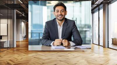 Portrait of young hispanic businessman inside office, boss in business suit smiling and looking at camera, experienced satisfied man at workplace at desk. Wall mural