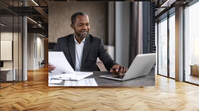 Professional african american businessman working at office desk with laptop and documents Wall mural