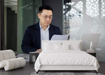 Professional Asian businessman reviewing documents in office Wall mural