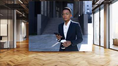 serious female student thinking, holding and using phone, african american business woman with cup o Wall mural