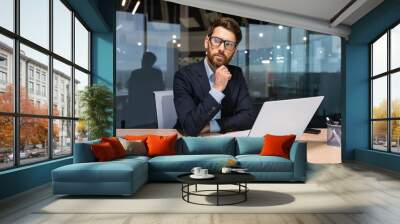 Serious thinking senior businessman working inside office using laptop, man in glasses solving problem, mature investor in business suit. Wall mural