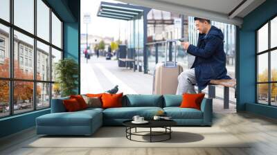 Tourist at the bus station, orders a taxi using the application on the phone, Asian book accommodation online for business travel Wall mural