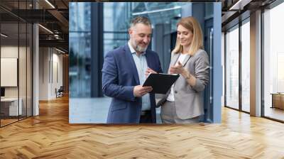 Two business colleagues man and woman talking and discussing work process, group of colleagues outside office building Wall mural