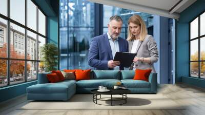 Two colleagues are concentrating and thinking, a man and a woman in business clothes are discussing business strategy, a group of business people outside an office building Wall mural